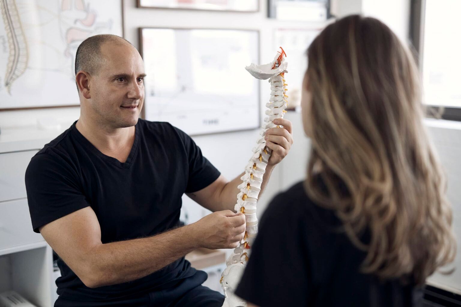 Chiropractor performing posture and spinal assessment.